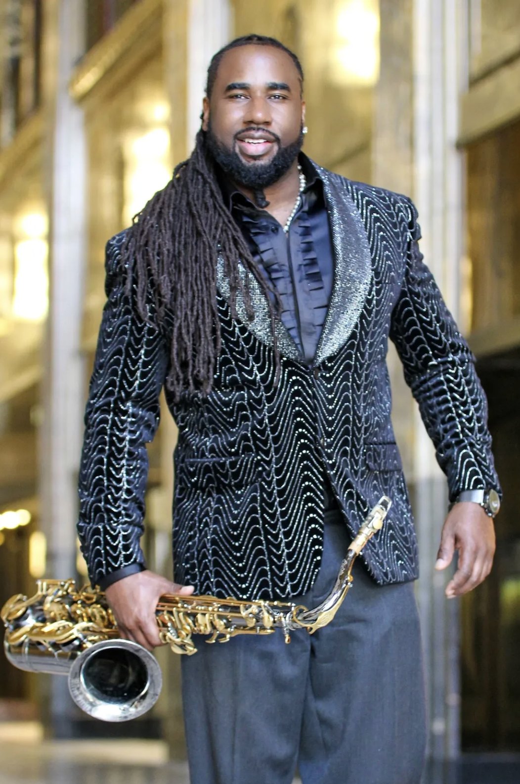 Lord Yancyy standing in a gilded lobby in a beaded dinner jacket, holding a gold saxophone